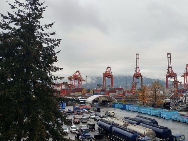 a shipping yard with cranes, cars and containers.